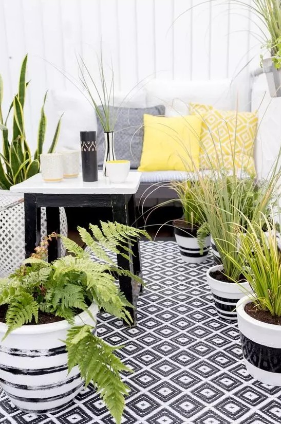 balcon avec tapis noir et blanc et coussins jaunes